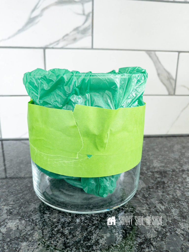 Painters tape and shopping bag are used to protect areas of a clear glass vase from primer and paint for this high-end color block vase dupe.