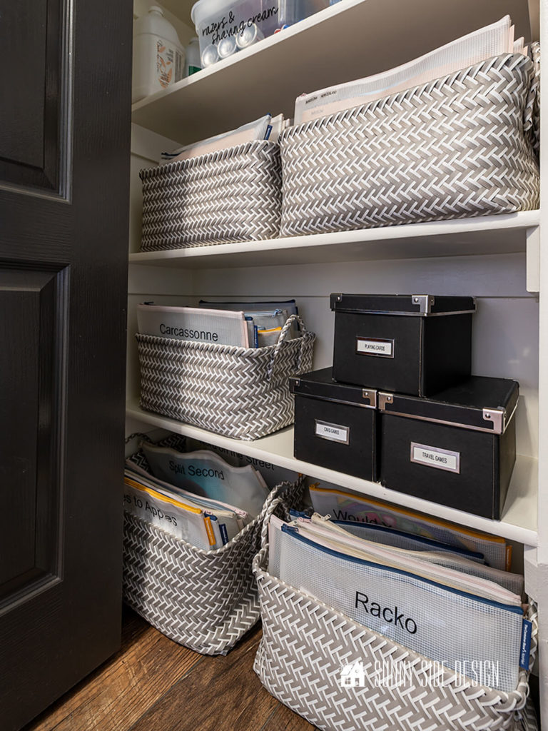 Gray and white baskets are used to organized games in labeled zippered pouches.