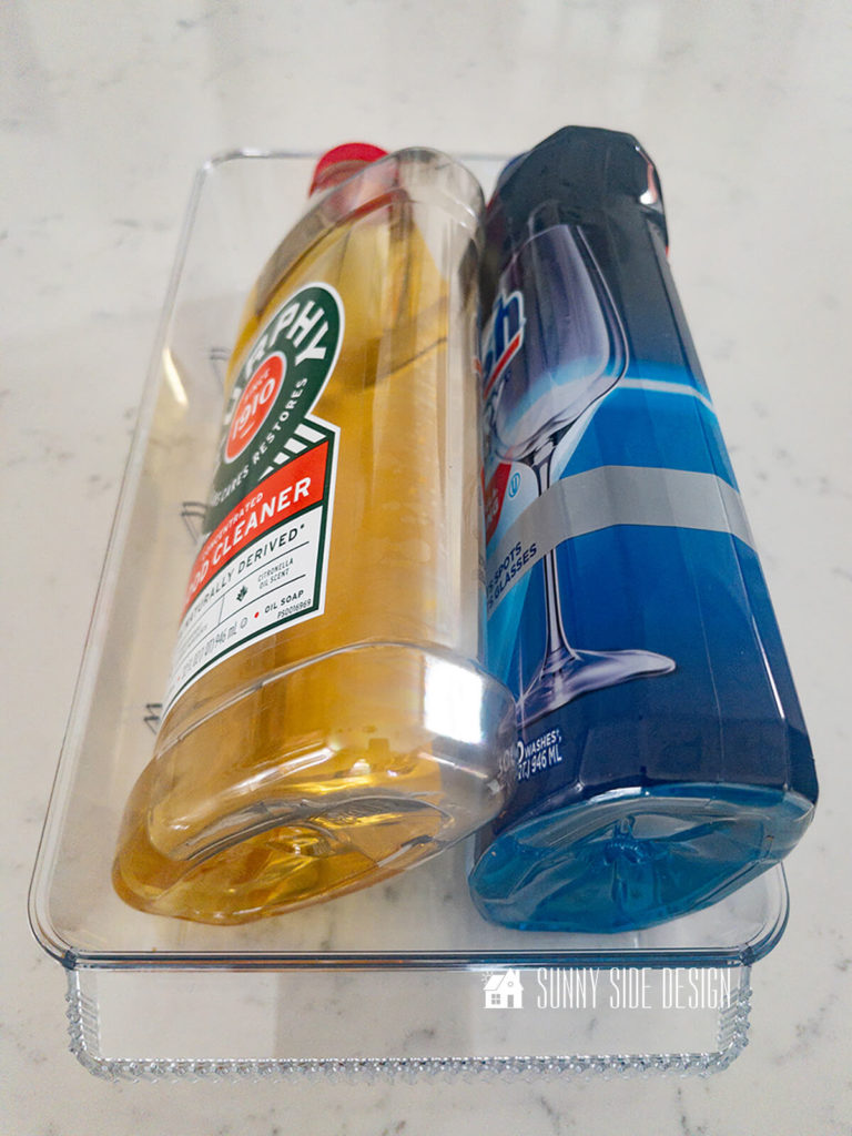 Kitchen clean supplies are stored in clear acrylic bins.