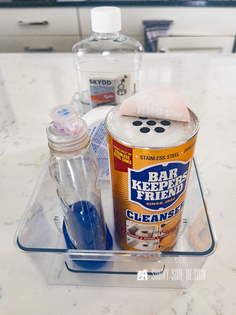 Kitchen clean supplies are stored in clear acrylic bins.