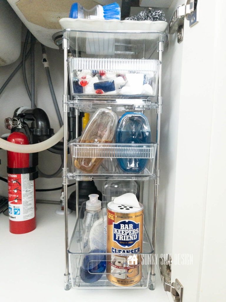 Under kitchen sink storage rack with sliding drawer, which holds, cleanser, dish washing liquid, Murphy's oil soap, finish, dishwasher tabs, scrub brush.