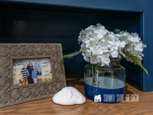Navy blue Pottery Barn color block vase dupe with white hydrangeas, styled with framed family photo and a sand dollar.