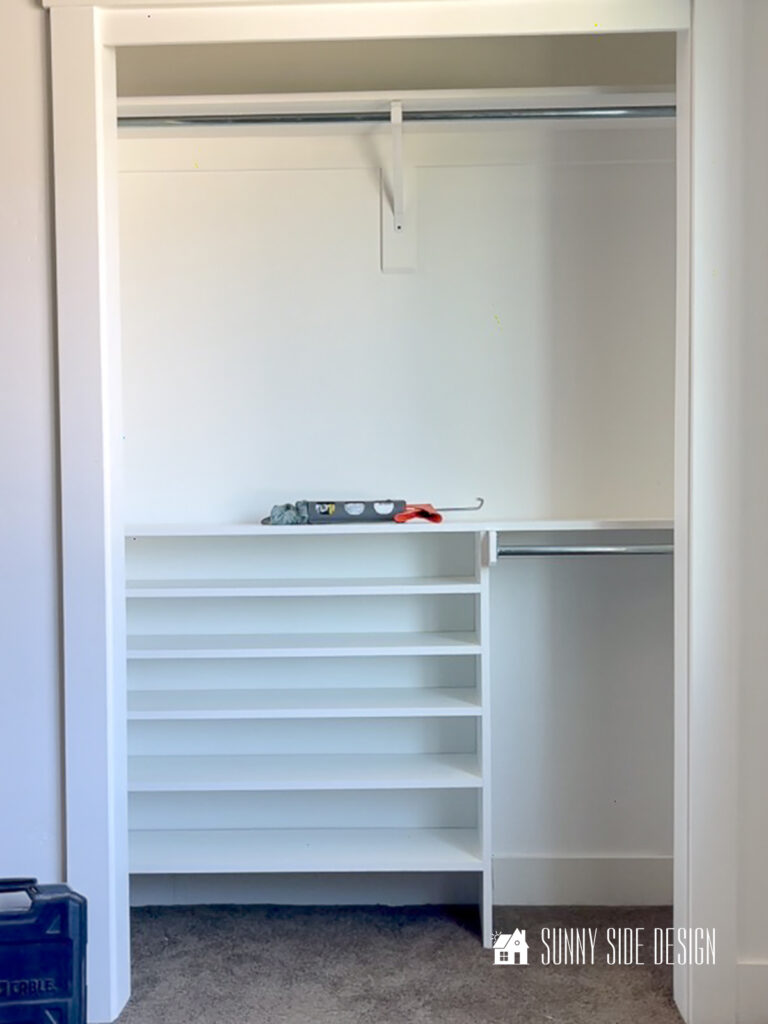Custom DIY closet organizer, with cubbies for shoe storage and closet rods for hanging clothing.