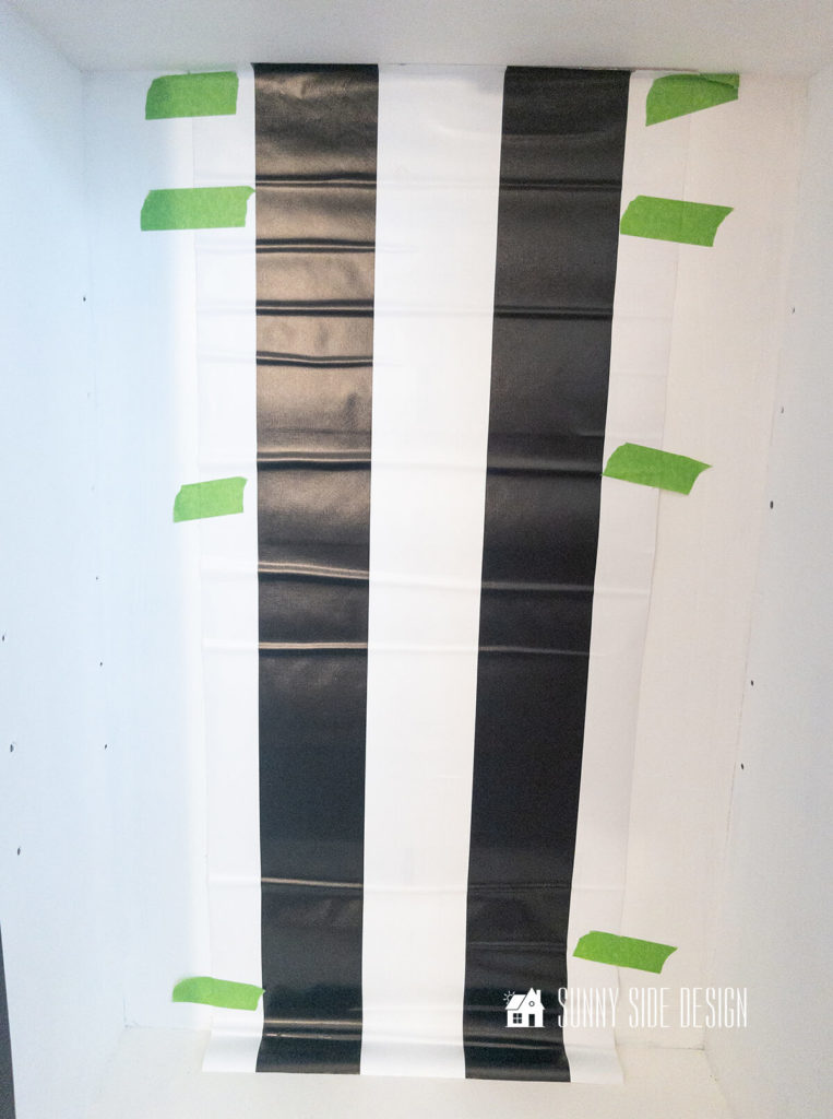 Wallpaper is placed to the back of the hutch top, with painters tape with the pattern centered