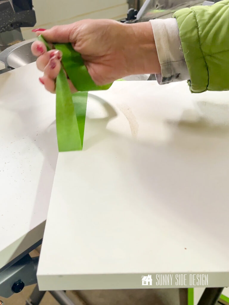 Masking tape is removed from the melamine shelf after cutting, showing no chipping.