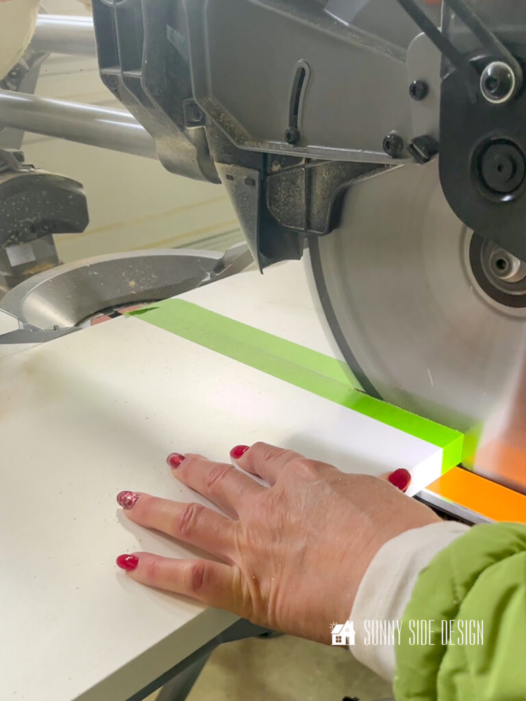 Masking tape is applied to melamine shelf and is cut with the miter saw.