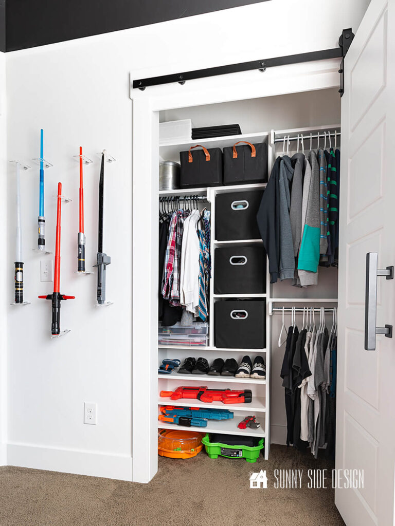 DIY closet organizer with a white bifold sliding barn door for easy access.