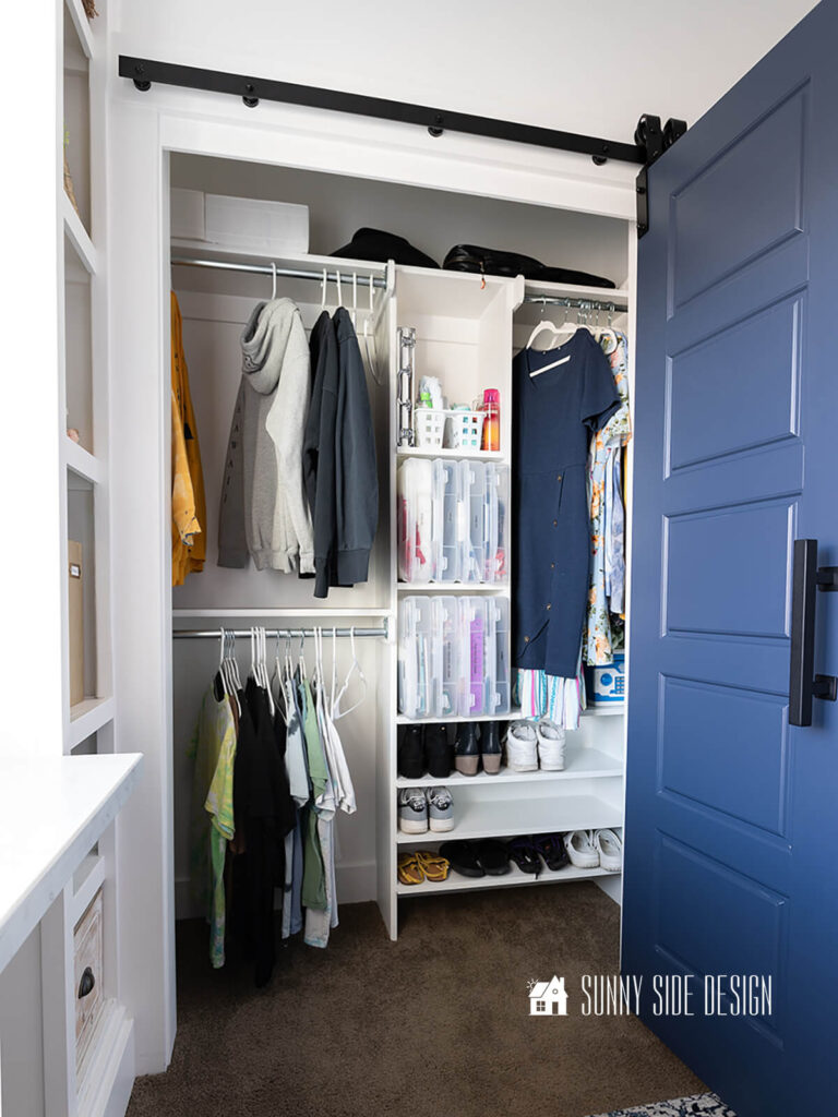 DIY closet organizer with a navy blue bifold sliding barn door for easy access.