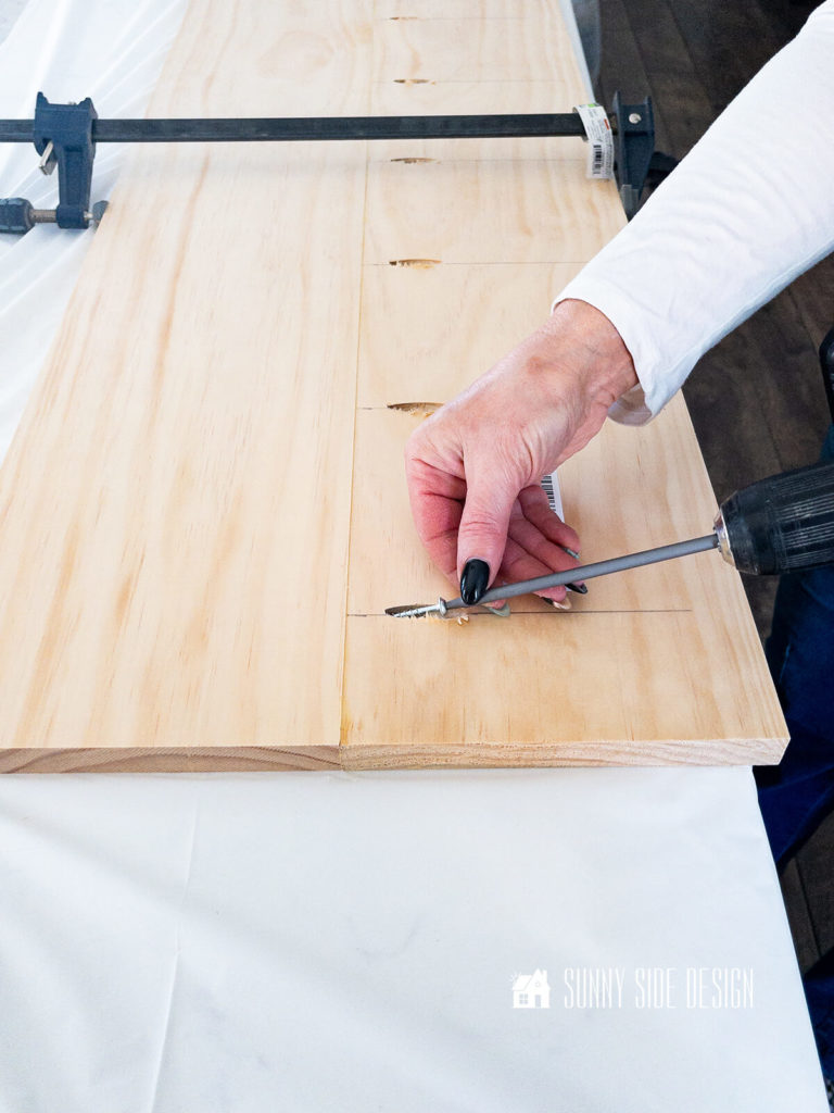 Pocket screws are inserted to boards to make a new top for the hutch.