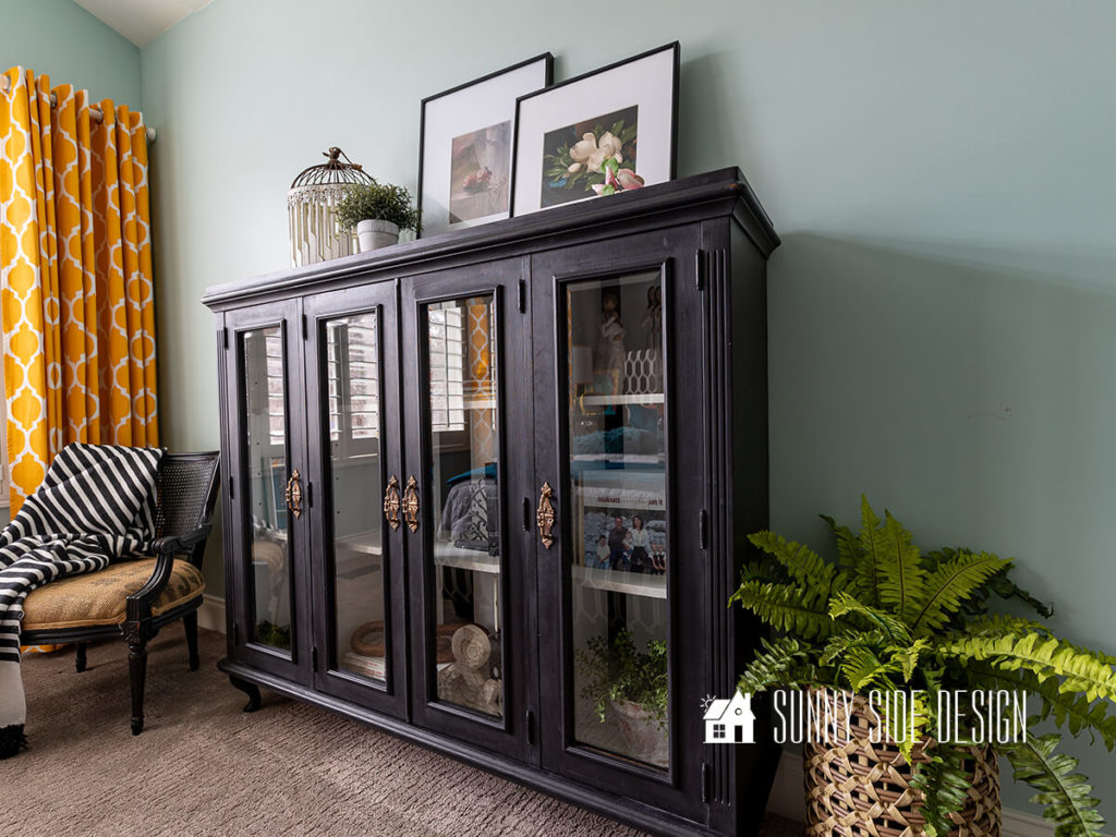 French-inspired bookshelves with glass doors made from a repurposed hutch top. Styled with art, books, plants.