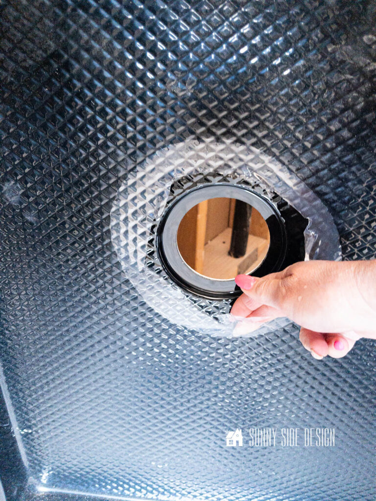 The protective film is cut back from the hole before we install a shower pan to the bathroom floor.