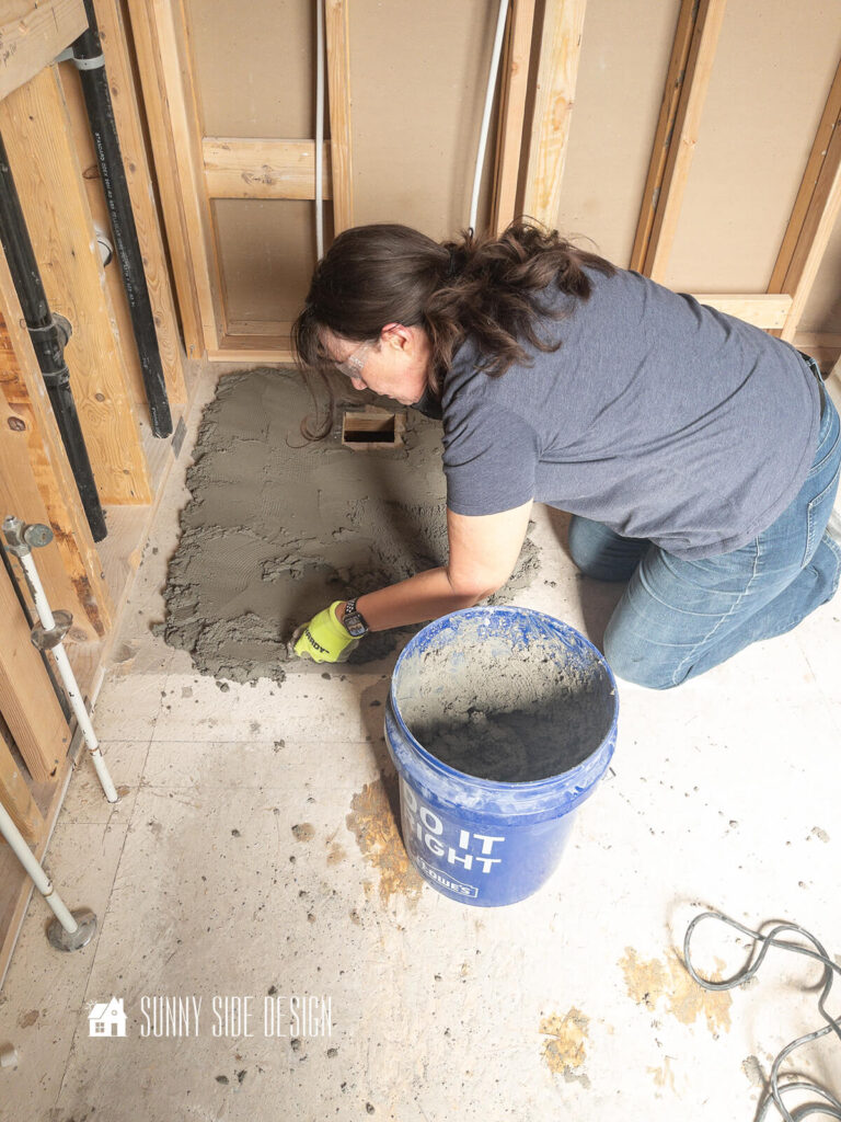 Mortar is applied to the subfloor to prepare to install a prefab shower pan in this bathroom remodel.