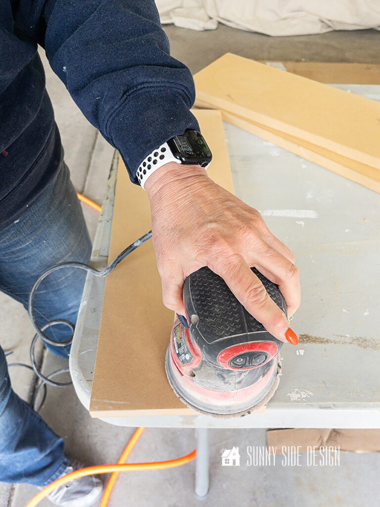 Woman sands edges of recessed shelf.