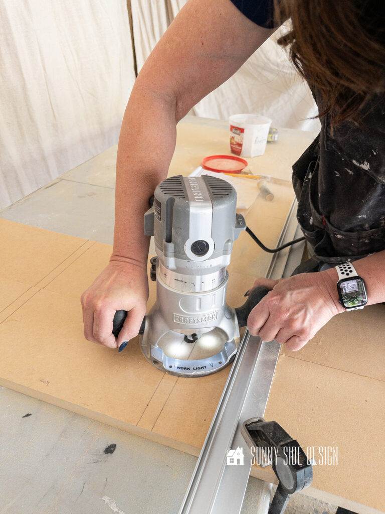 Woman guiding a router along the two side pieces for the bathroom recessed shelf in a wall.