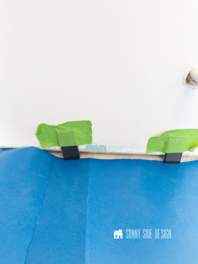 Spacers are taped to the wall before installing luxury vinyl plank flooring.