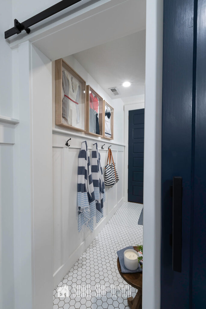 Board and batten wall with hooks in a modern coastal bathroom with vintage swimsuit art.