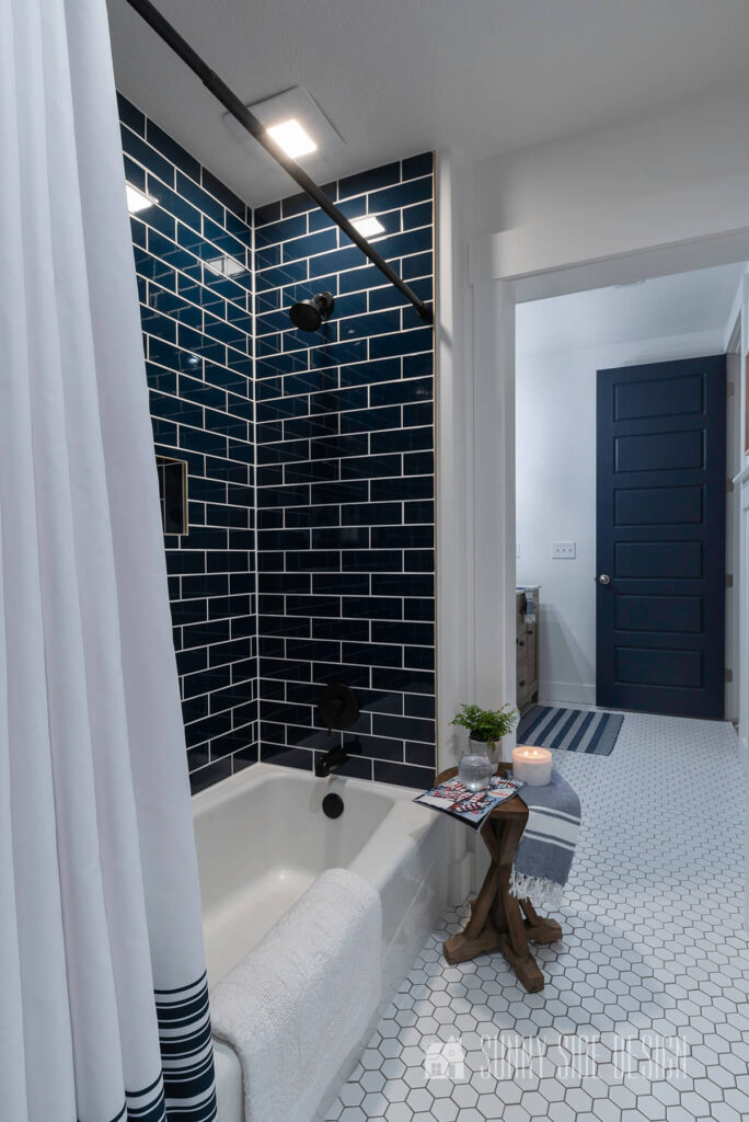 Home tour Modern coastal bathroom with navy blue subway tile, matte black fixtures, white hexagon tile and navy blue door.