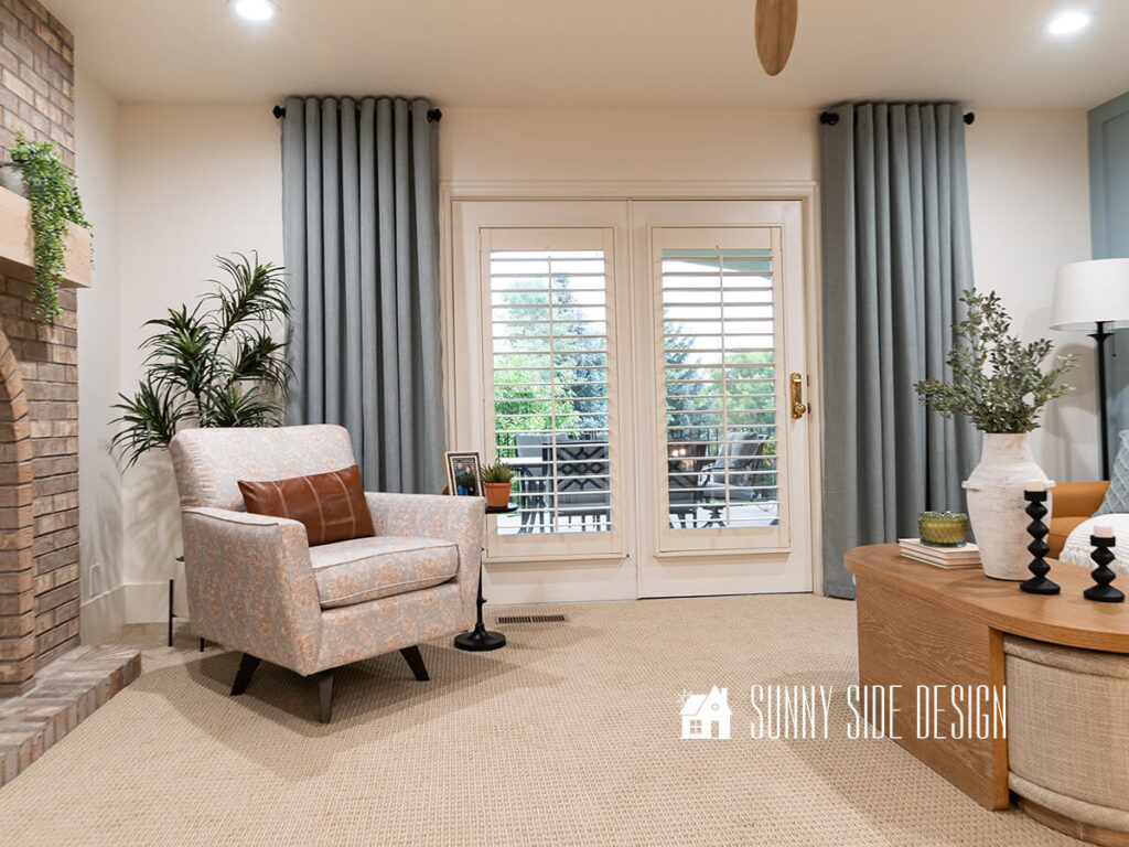 White plantation shutters let in light through the French doors. The curtains are hung high and wide to allow as much light into the room as possible. They also make the ceiling feel taller.