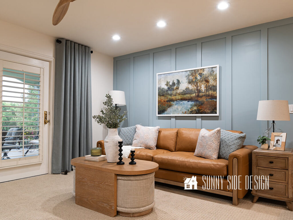 A colorful large piece of art is hung above the caramel leather sofa. Cerused oak coffee table with beige ottomans for extra seating. Pillow is decorated with light colored pillows.