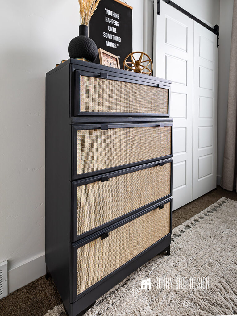 A vintage dresser is restored with black paint, cane and screen moulding.