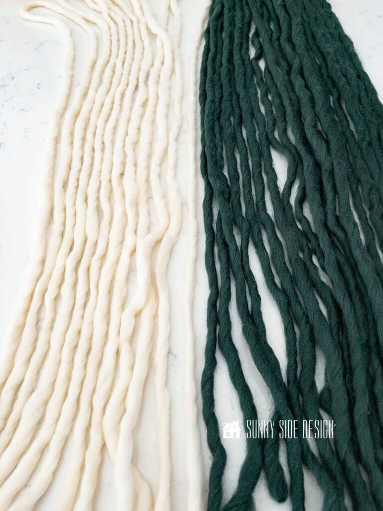 Cream and green roving yarn are cut to length for the yarn wall art.