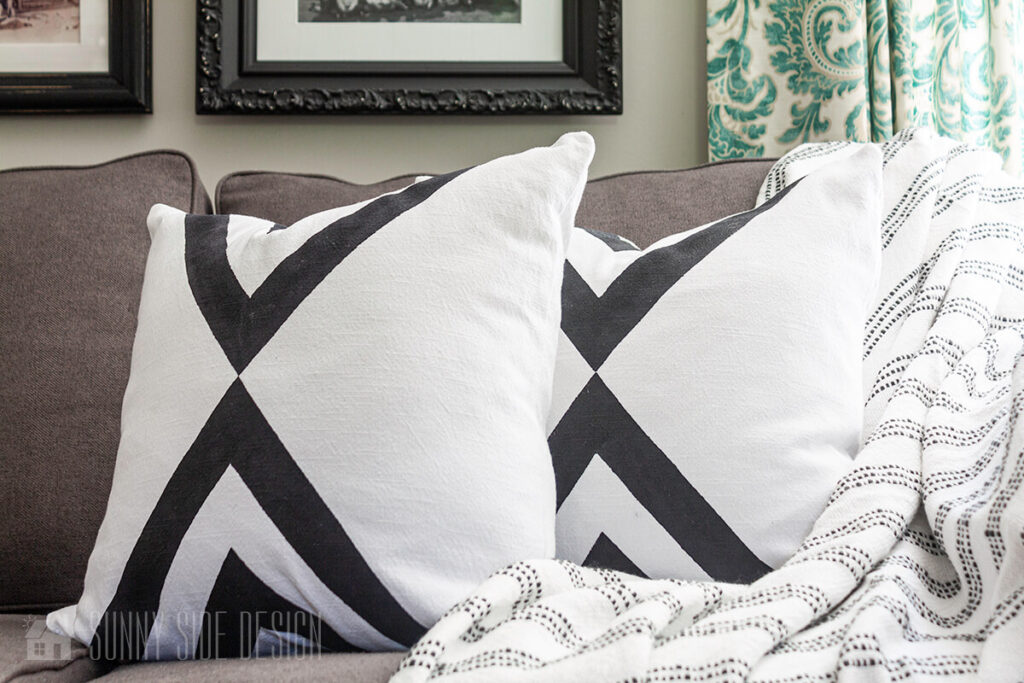 Upcycled ideas: a stained white tablecloth is repurposed into two throw pillows with paint.