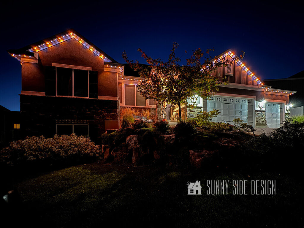 Halloween exterior house lights in shades of purple and orange.