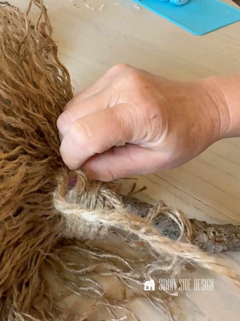 Woman forms a macrame loop know to finish off broom.