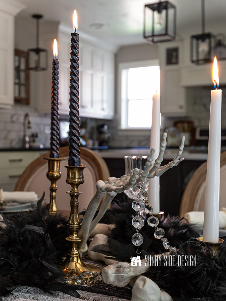 Halloween table decor ideas: skeleton bones are scattered on top of the lace and creepy cloth table runner along with black birds, feathers and strands of vintage chandelier crystals.