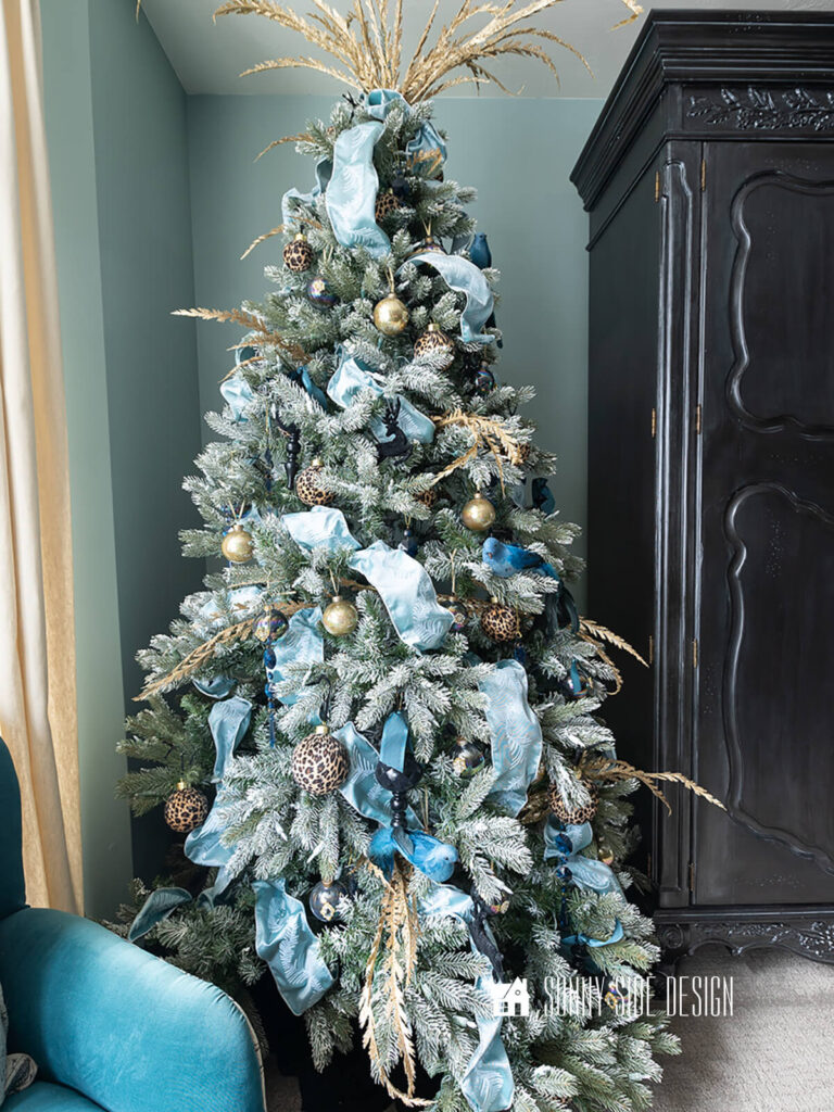 Styled Christmas tree in a bedroom with blue walls. Tips for putting ribbon on a Christmas tree, cascading ribbon garland.