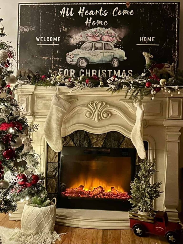 Christmas Decorating Ideas for Mantle, with traditional red and green garland and ornaments, white stocking are hung from the mantle and large oversize Christmas art is placed above the mantle.