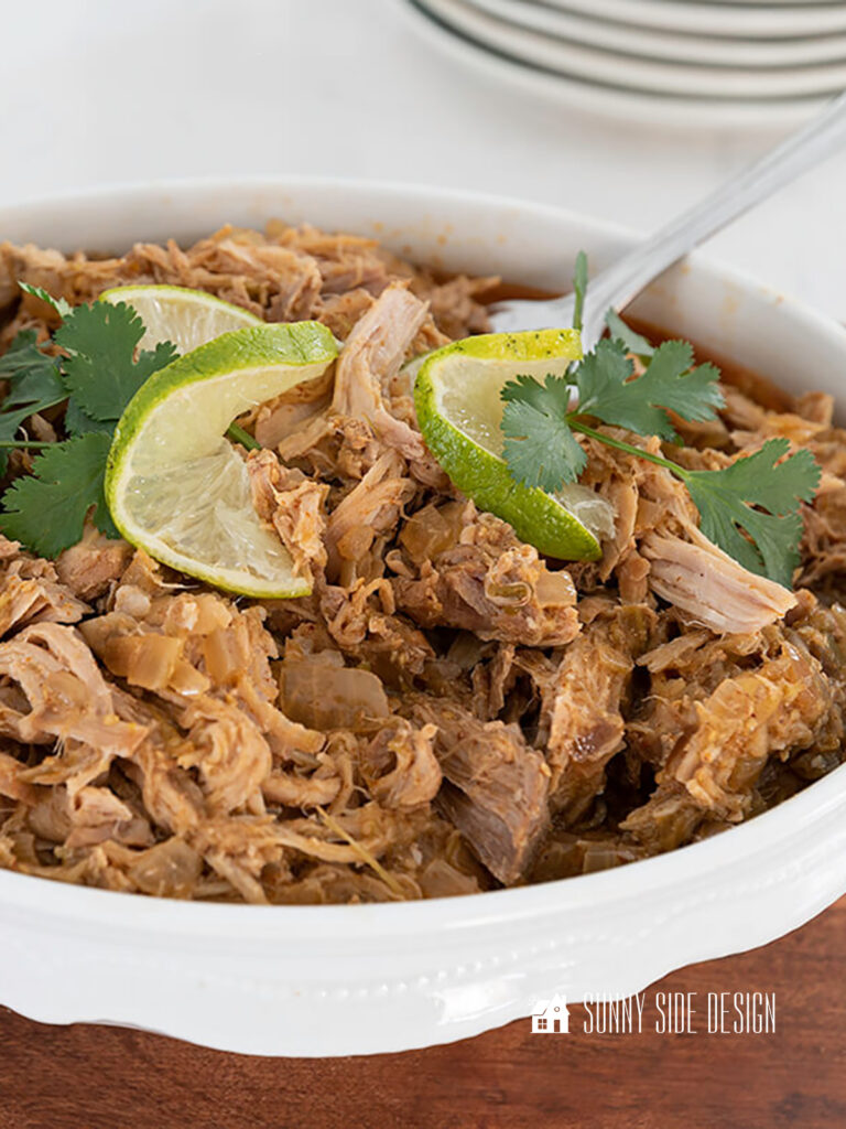 Crockpot Pork Loin Recipe, shredded and garnished with cilantro and limes.