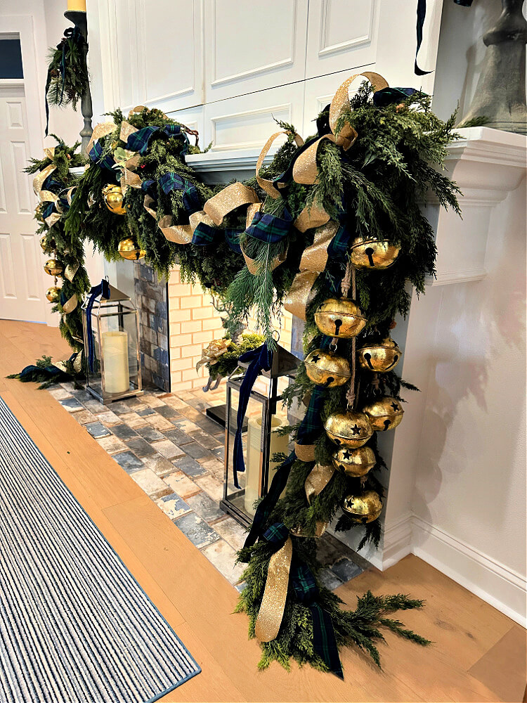 Regency-core inspire grand garland draped across and down the mantle sides, embellished with large brass bells and blue and gold ribbon.