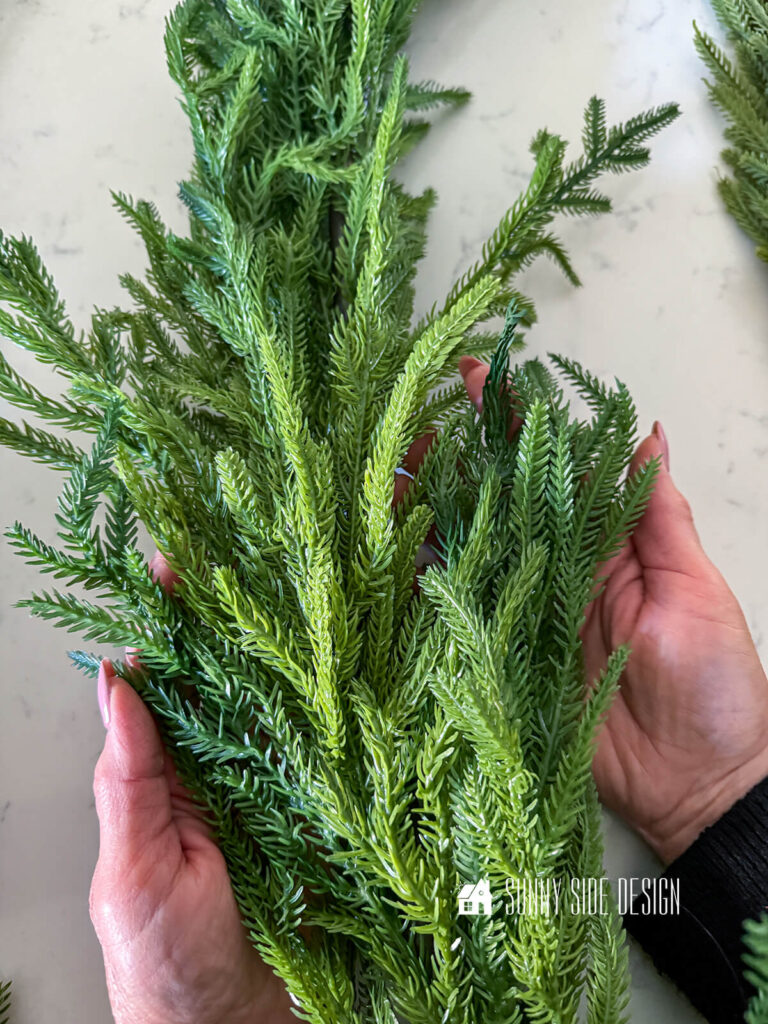 Woman holds a faux garland with variations of greens.
