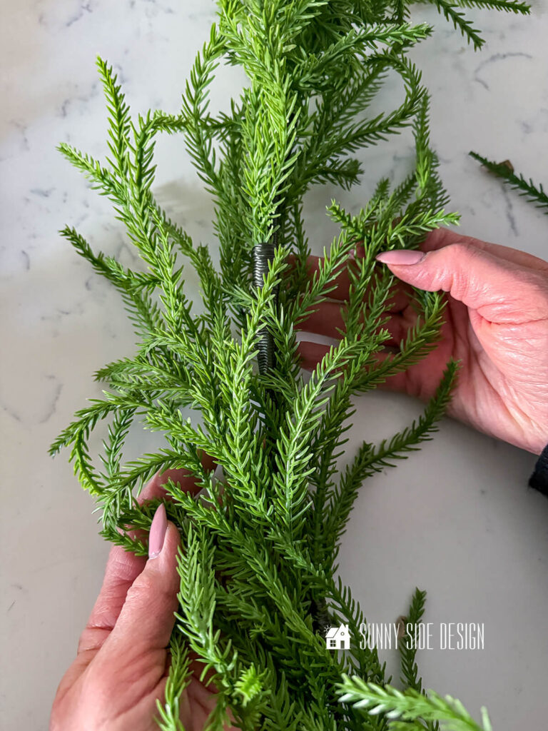 Woman holds pine garland.