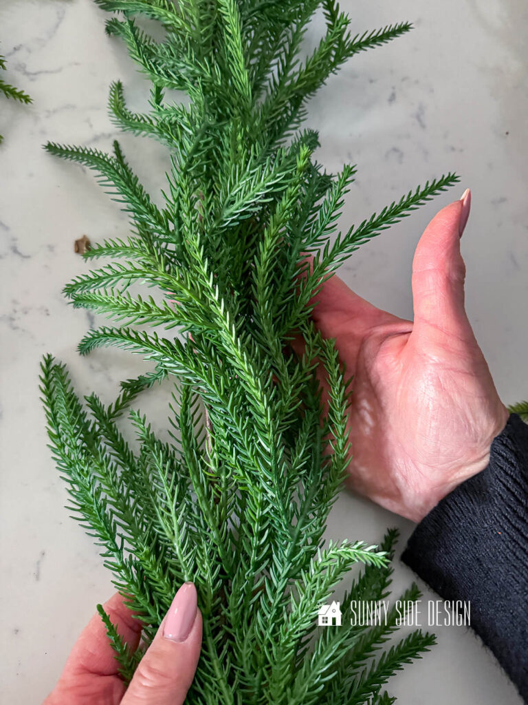 Woman holds green pine garland.