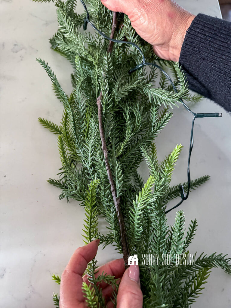 Woman's hangs show the back side of a pine garland.
