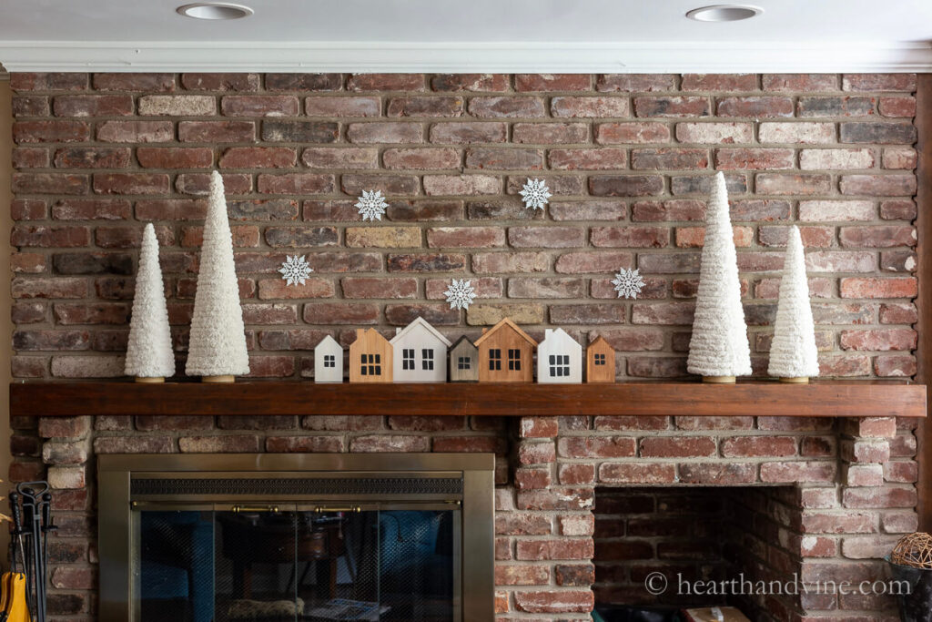 Simple Christmas mantle decor with a painted wood Christmas villate and yarn trees.