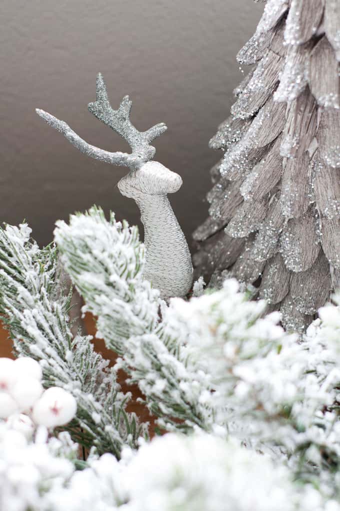 Create a faux mantle with a garland, trees and reindeer on a long piece of furniture.