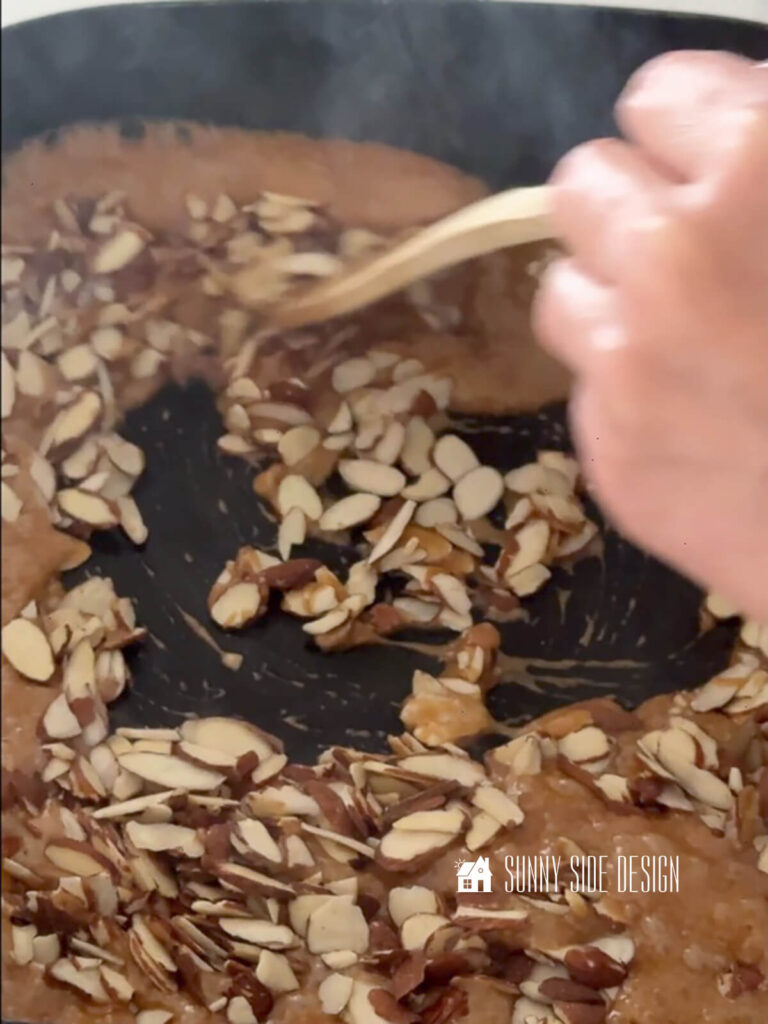 Stirring in nuts to the toffee with a wooden spoon.