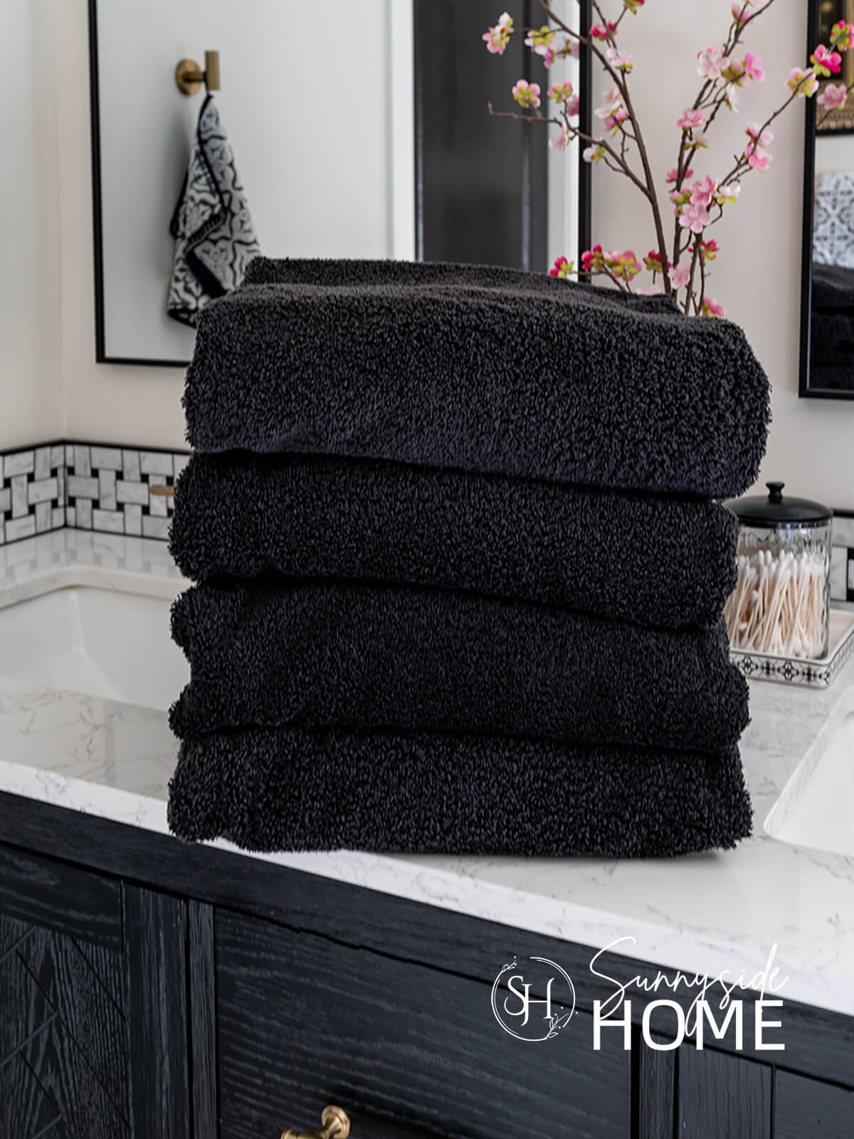 Clean stacked black bath towels on the bathroom counter.