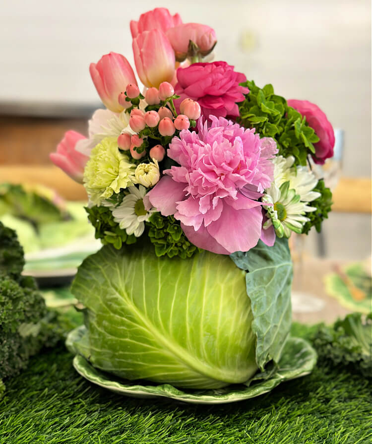 Cabbage vase filled with fresh pink and green flowers form a pretty centerpiece for this spring tablescape.