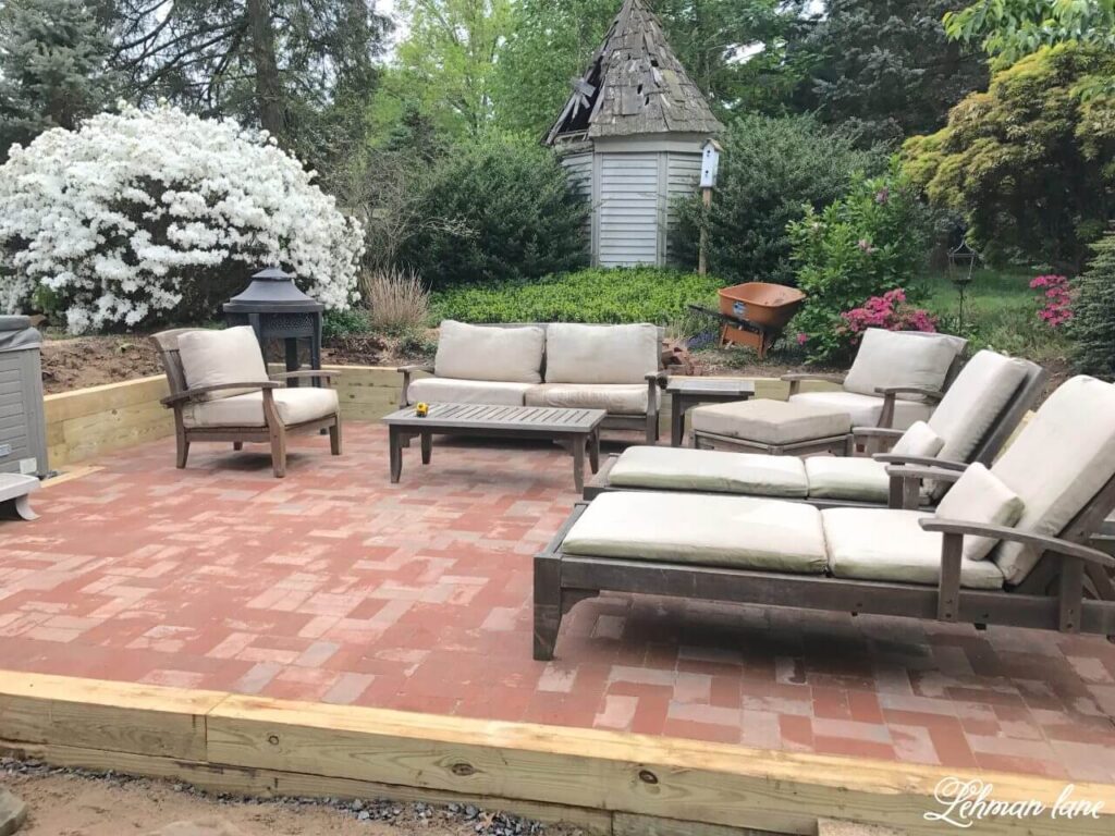 Raised red brick paver patio styled with an outdoor seating area and lounge chairs.