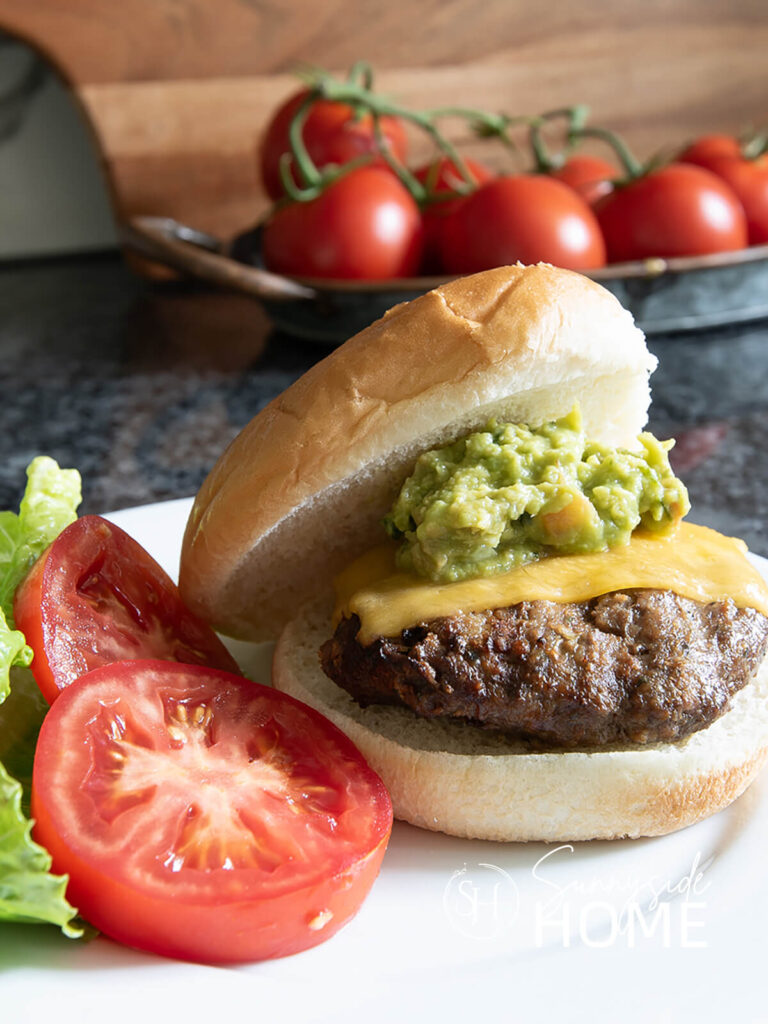 Recipes for Summer: Chipotle spiced burger garnished with cheddar cheese, guacamole, tomatoes and lettuce.