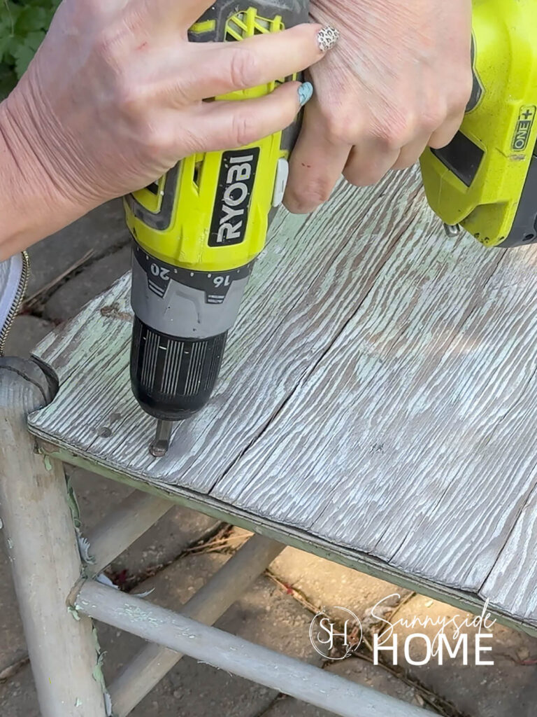 Woman's removes the screws from the seat of a vintage ladderback chair.