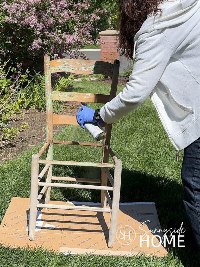 Woman applies an outdoor sealer to a vintage ladderback chair.