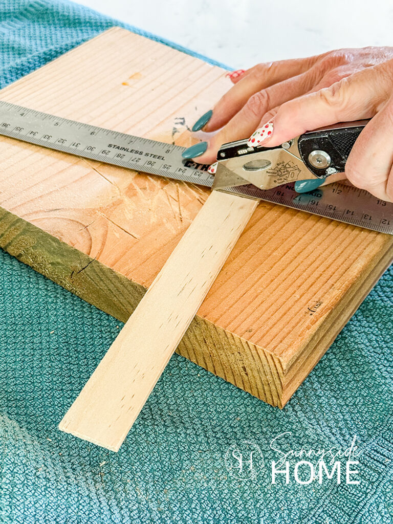 Woman scores stir stick with a utility knife to cut into pieces for patriotic decor.