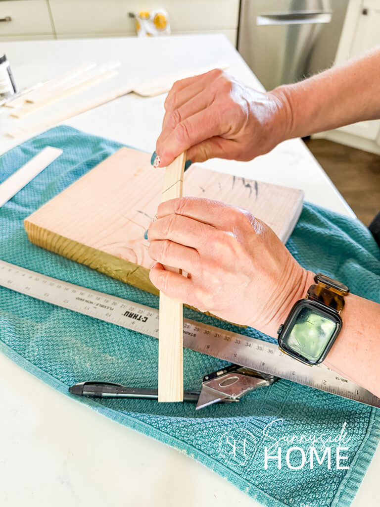 Woman snaps paint stir stick in half.