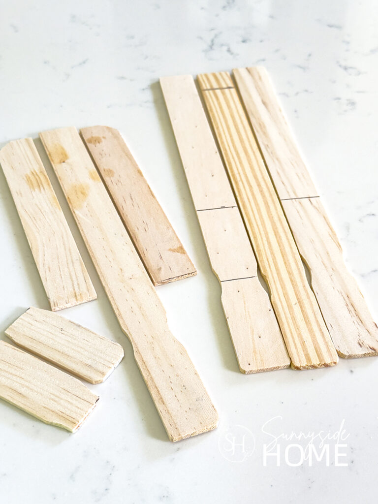 Paint stir stick marked with cut lines, also cut into pieces to form patriotic popsicle decor.