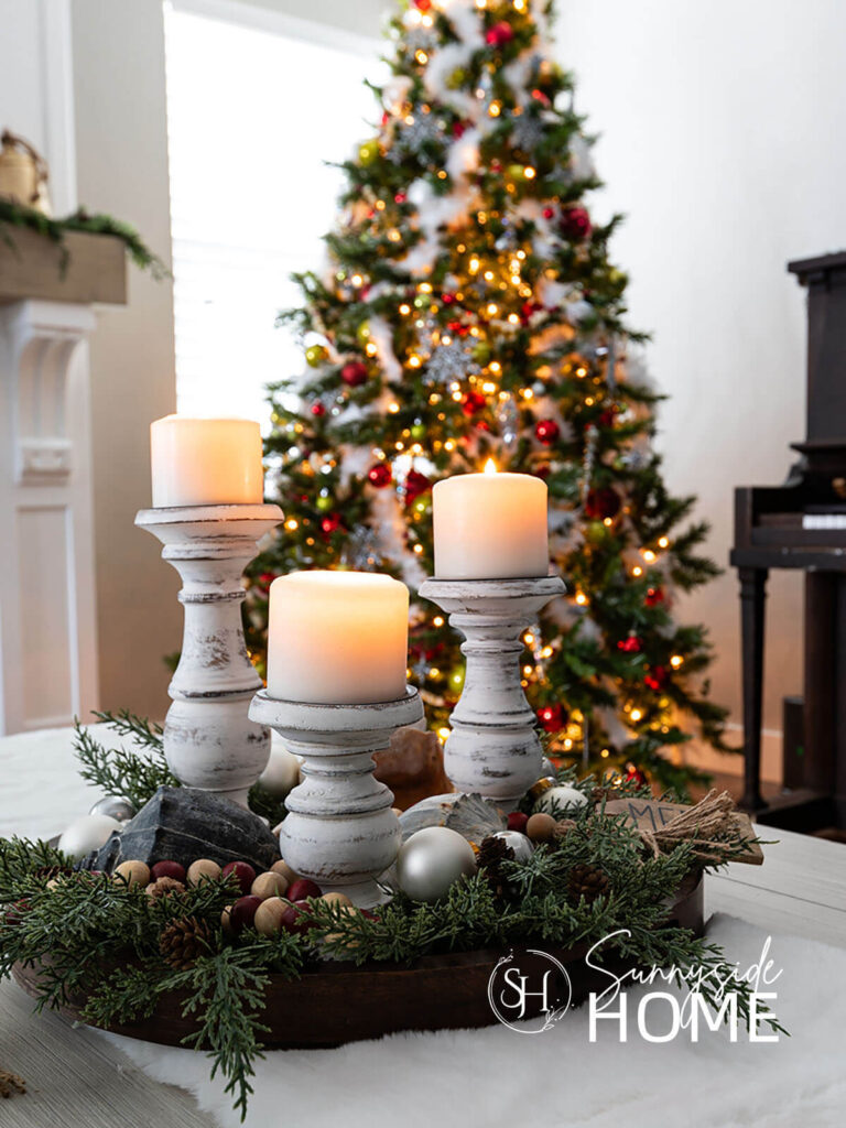 Candle centerpiece on the coffee table with a decorated Christmas tree in the background.